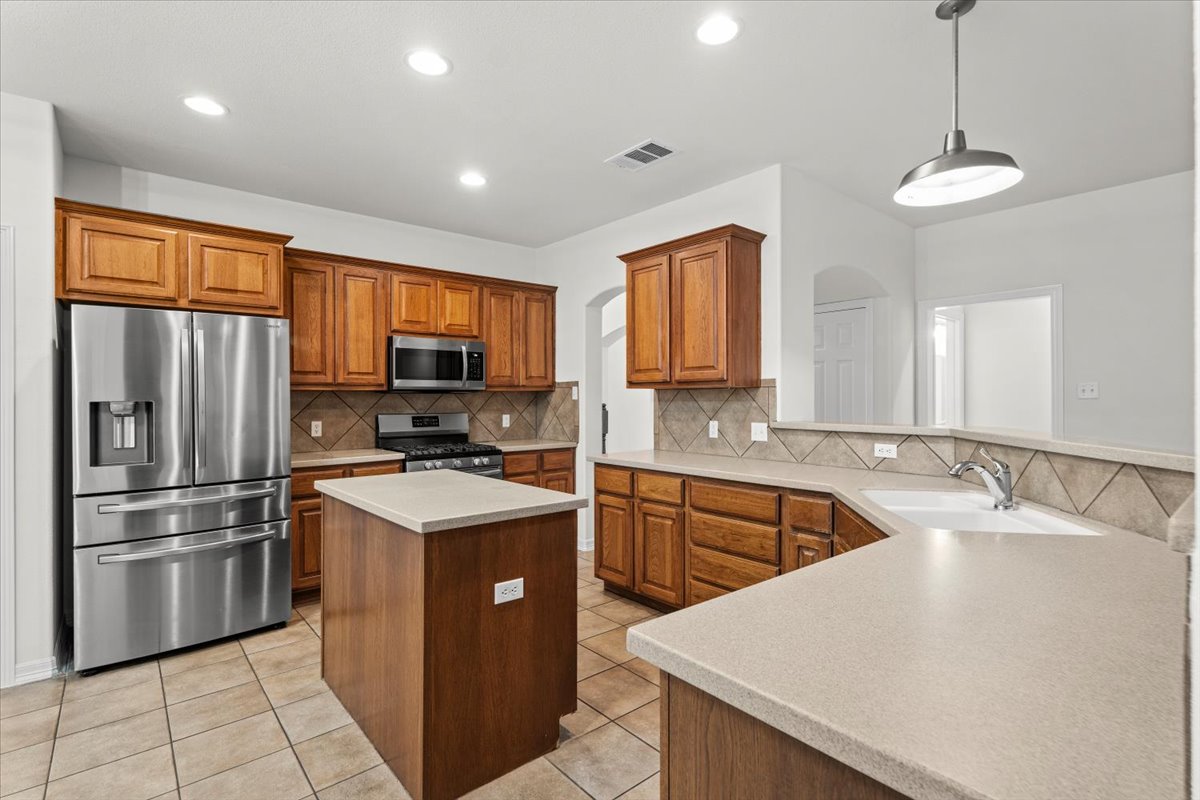 2304 Village View Loop Pflugerville, TX 78660 - Photo 8 of 40 A well-equipped kitchen featuring warm wood cabinetry, neutral countertops, and modern stainless steel appliances.