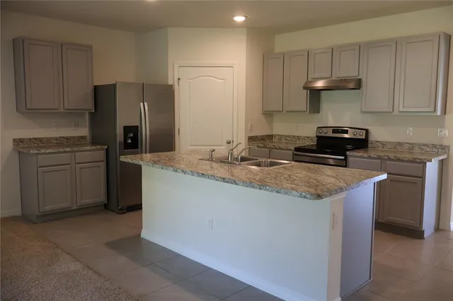 a kitchen with kitchen island granite countertop stainless steel appliances stove a sink and refrigerator
