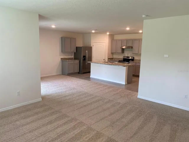 a large kitchen with a refrigerator a counter top and a stove top oven