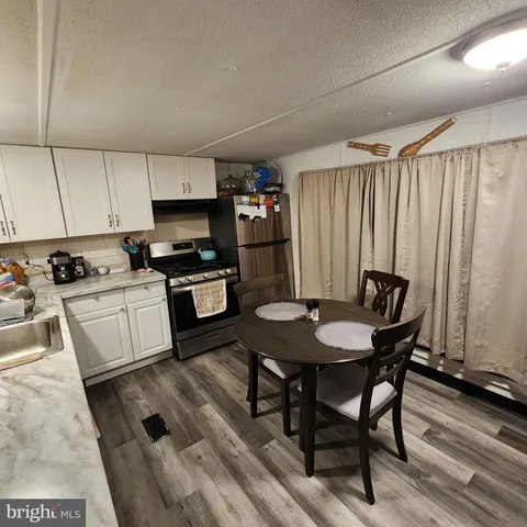 a kitchen with stainless steel appliances kitchen island granite countertop a table chairs sink and cabinets