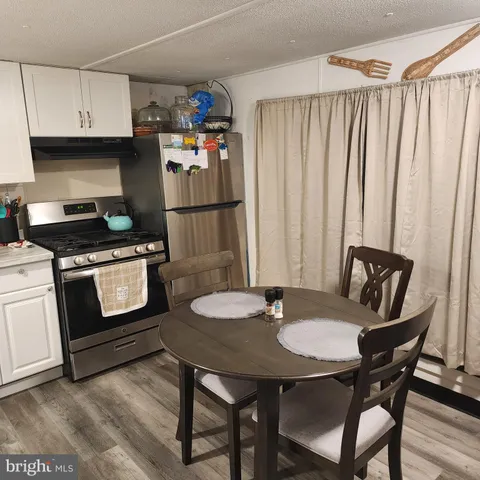 a kitchen with stainless steel appliances a table chairs and a refrigerator