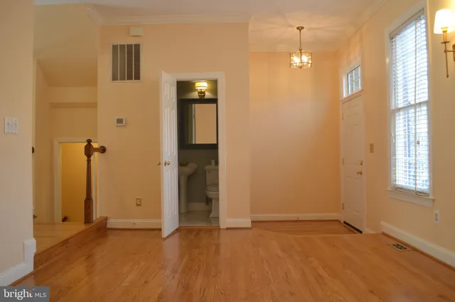 a view of an empty room with window and chandelier fan