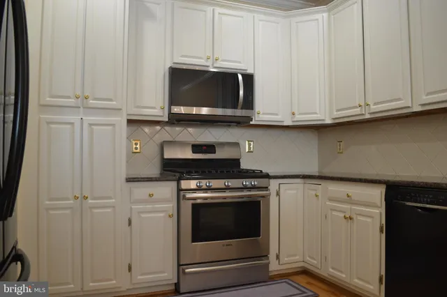 a kitchen with granite countertop white cabinets and stainless steel appliances