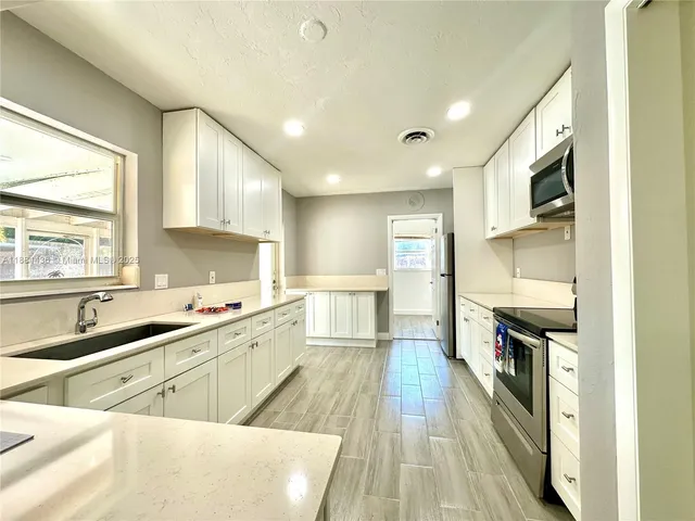 a kitchen with stainless steel appliances white cabinets sink and a microwave
