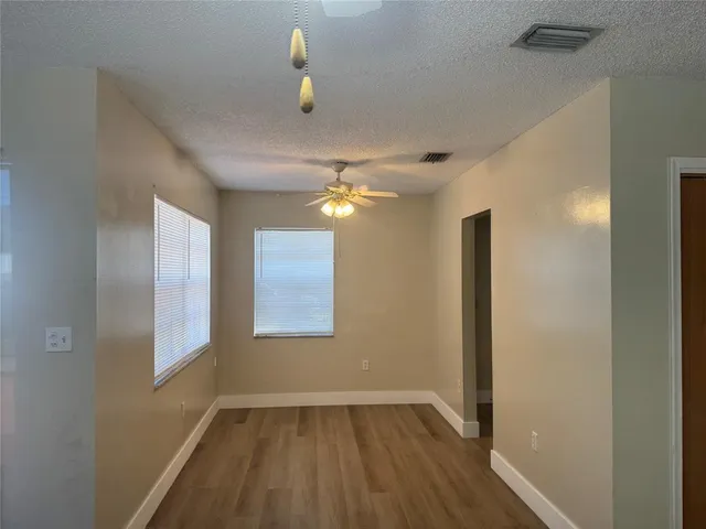 a view of an empty room with window and wooden floor