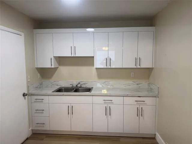 a kitchen with white cabinets and sink