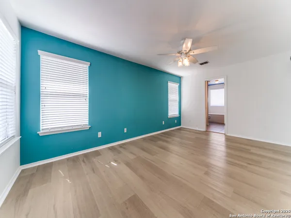 a view of an empty room with window and chandelier fan