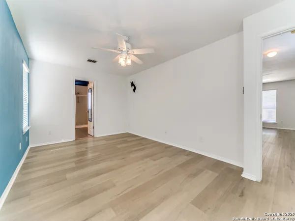 an empty room with wooden floor and ceiling fan