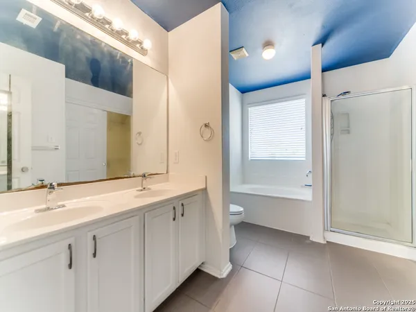 a bathroom with a double vanity sink toilet mirror and bathtub