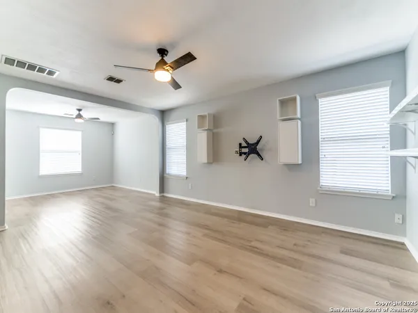 a view of empty room with wooden floor and fan