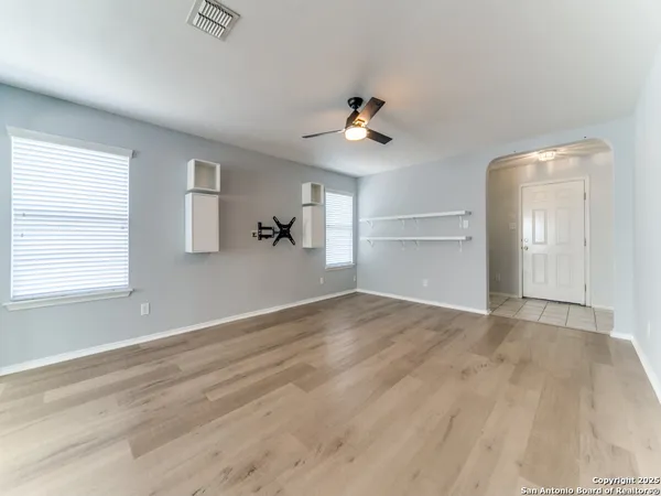 a view of empty room with wooden floor and fan