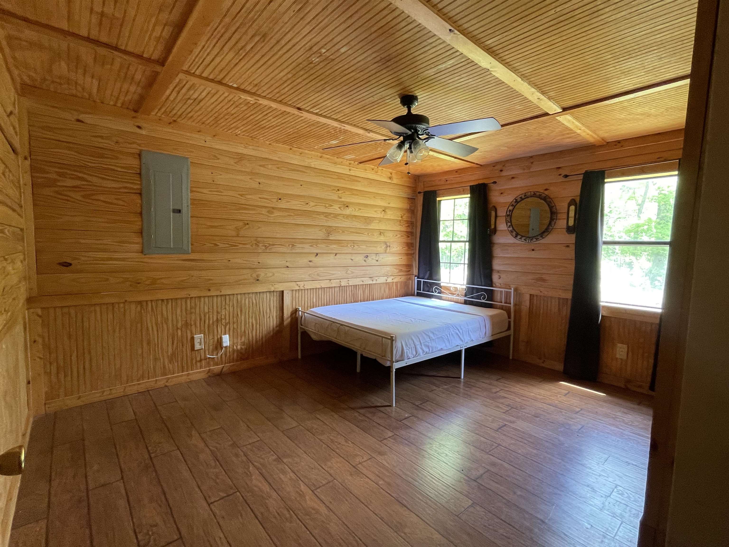 2349 Snyder Bluff Road Ripley, TN 38063 - Photo 12 of 21 Bedroom with wood walls, electric panel, wood ceiling, wood-type flooring, and a ceiling fan
