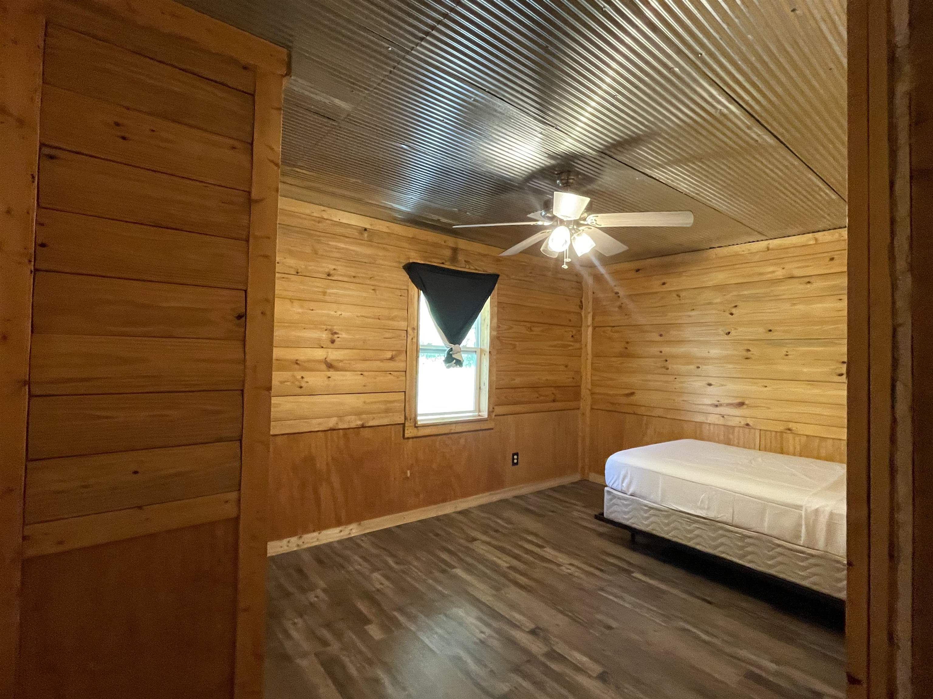 2349 Snyder Bluff Road Ripley, TN 38063 - Photo 13 of 21 Unfurnished bedroom with wood walls, ceiling fan, and dark wood-style flooring