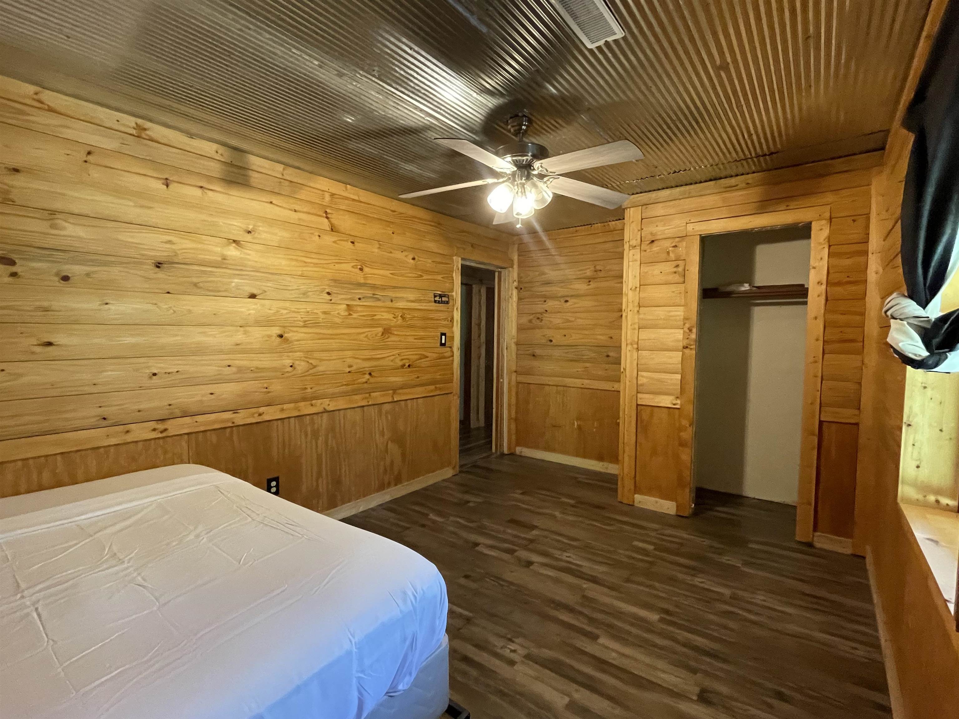 2349 Snyder Bluff Road Ripley, TN 38063 - Photo 14 of 21 Bedroom featuring wood walls, dark wood-style flooring, a closet, and ceiling fan