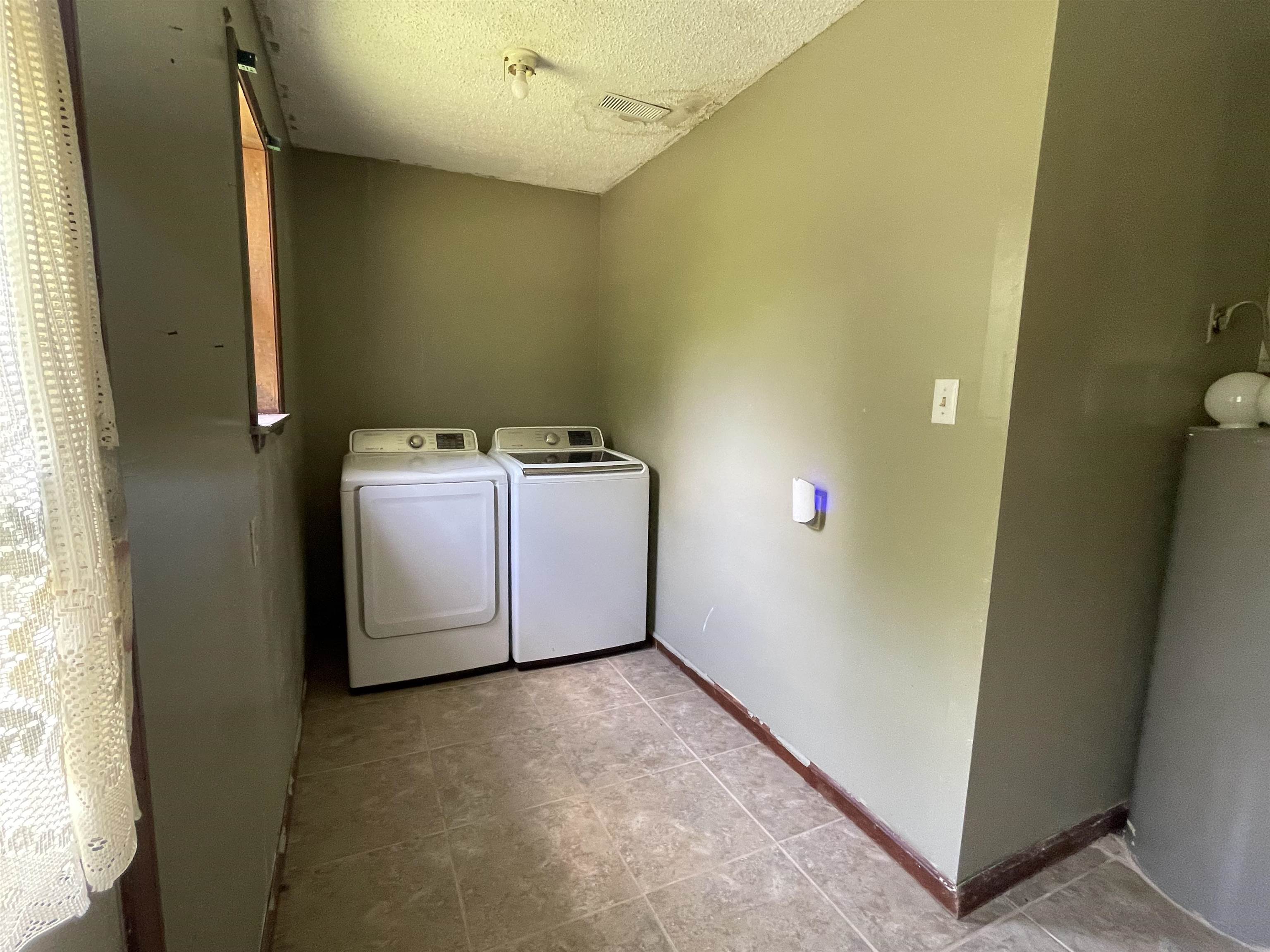 2349 Snyder Bluff Road Ripley, TN 38063 - Photo 18 of 21 Laundry area featuring washer and clothes dryer, water heater, and a textured ceiling