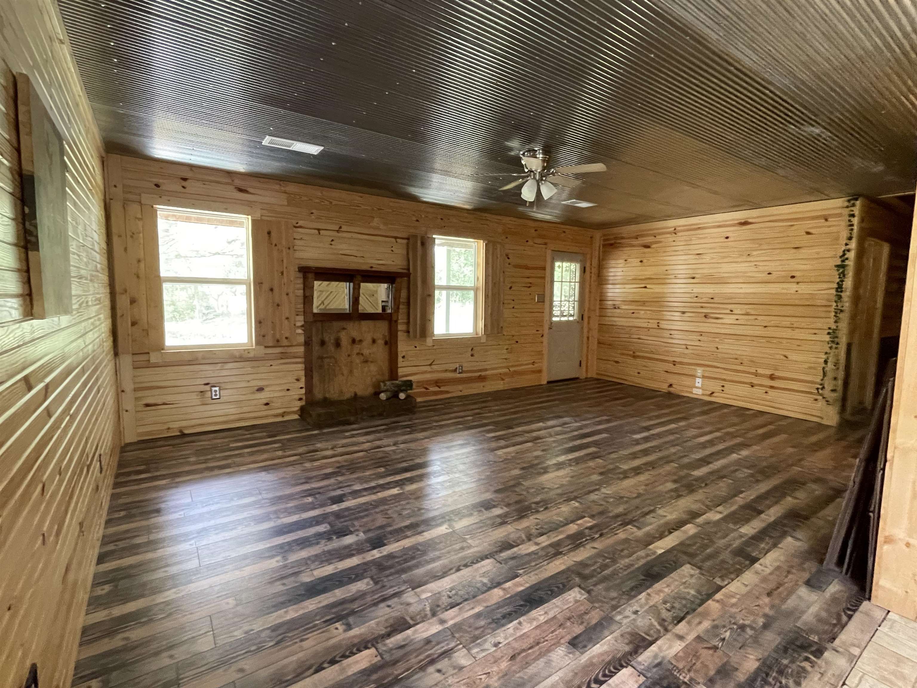 2349 Snyder Bluff Road Ripley, TN 38063 - Photo 4 of 21 Unfurnished living room featuring wood walls, hardwood / wood-style flooring, and a ceiling fan
