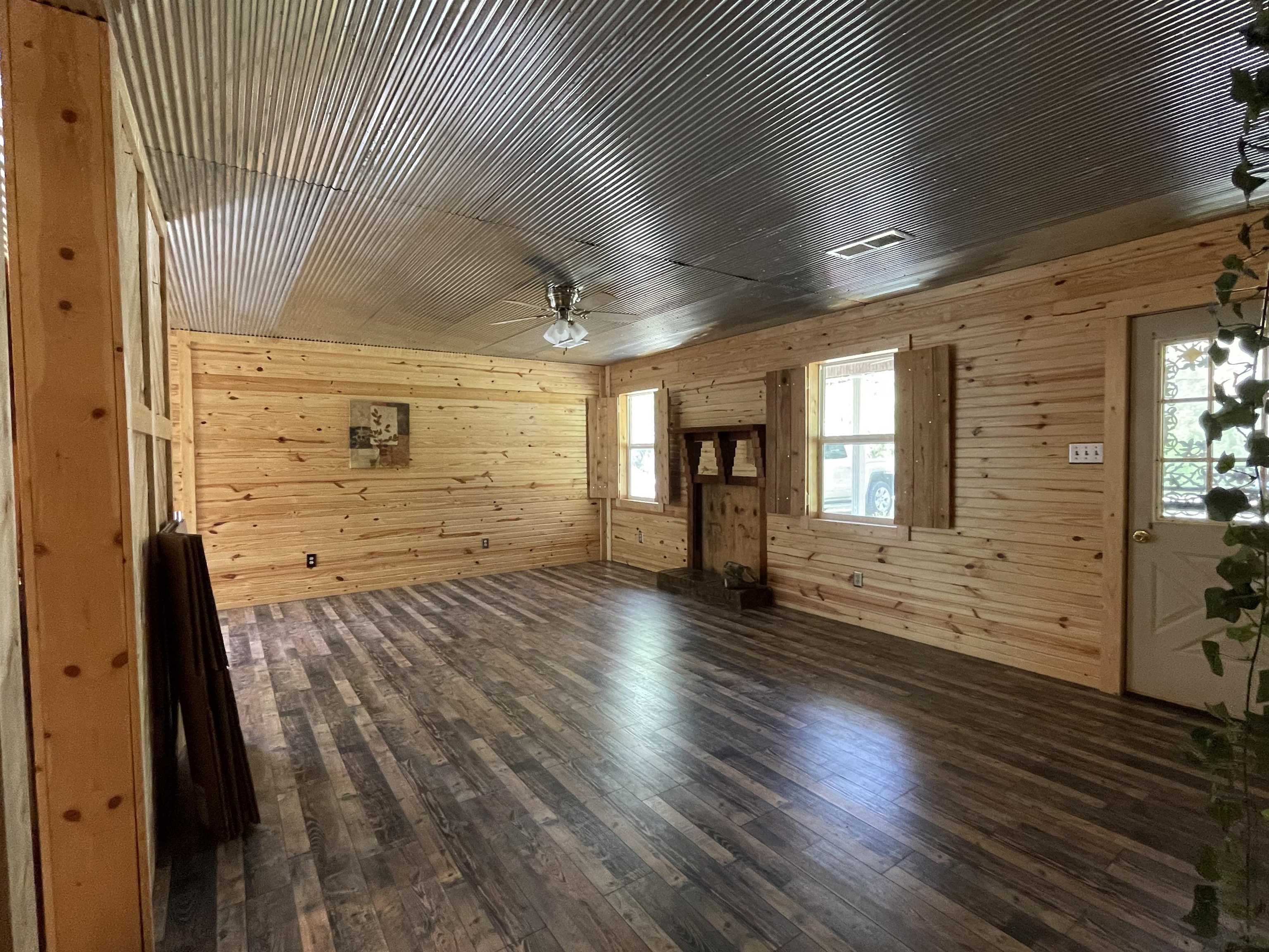 2349 Snyder Bluff Road Ripley, TN 38063 - Photo 5 of 21 Unfurnished living room featuring dark wood-type flooring, wooden walls, and a ceiling fan