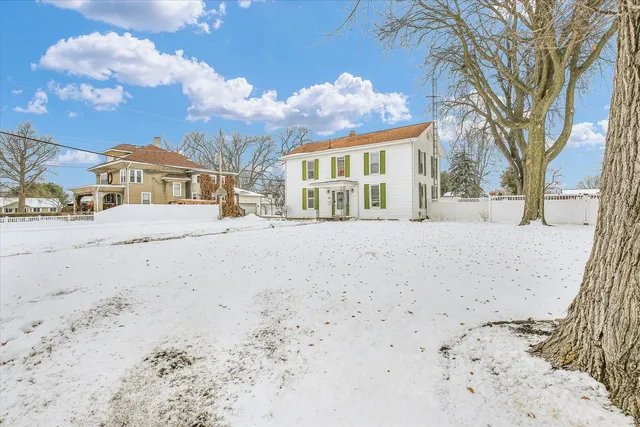 a view of a large white house with a snow in the yard