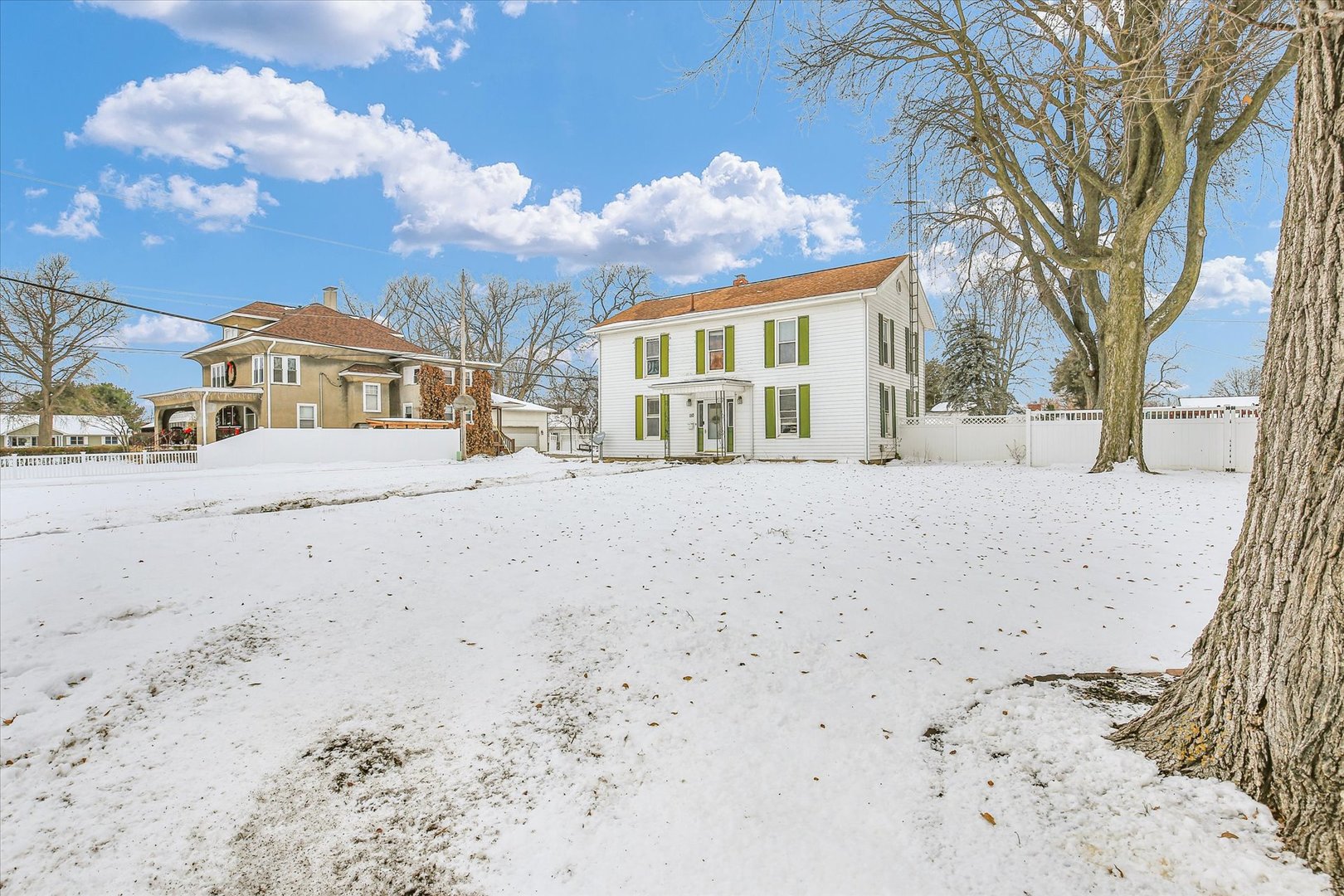 a view of a large white house with a snow in the yard