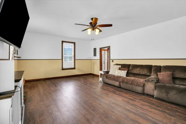 a living room with couches and a flat screen tv with kitchen view