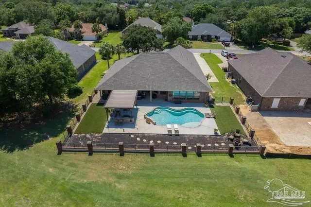 a aerial view of a swimming pool with lawn chairs and a yard