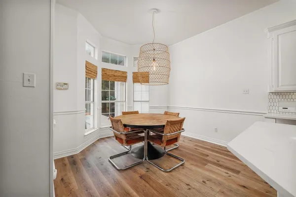 a dining room with wooden floor and white walls
