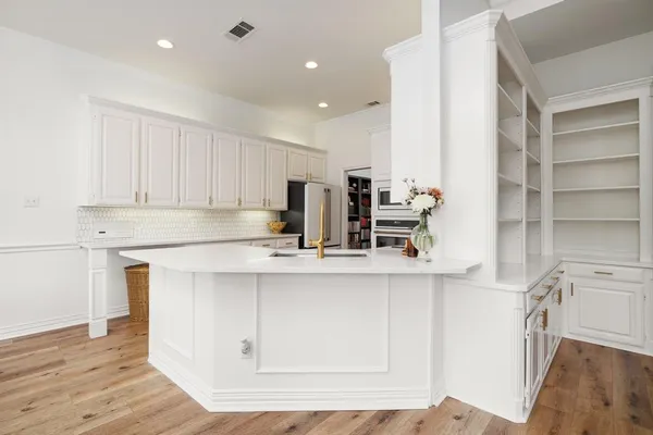 a kitchen with stainless steel appliances granite countertop a sink a stove and a wooden floors