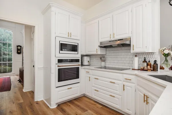 a kitchen with granite countertop white cabinets and stainless steel appliances