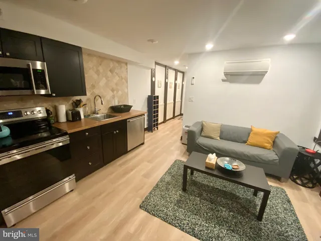a living room with stainless steel appliances furniture a rug kitchen view and a counter top space