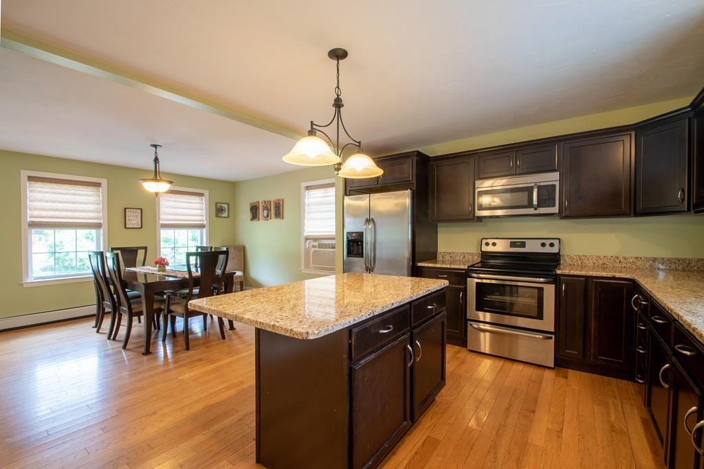 70 Frederick Street Fitchburg, MA 01420 - Photo 3 of 19 a kitchen with granite countertop a stove top oven a sink dishwasher a dining table and chairs with wooden floor