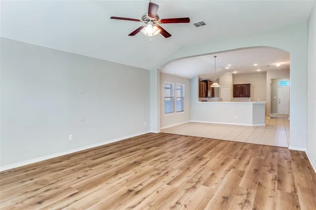 a view of empty room with wooden floor and fan