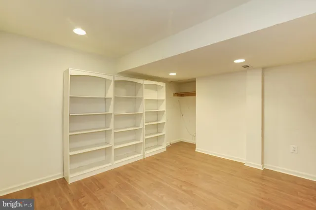 a view of an empty room with wooden floor and closet