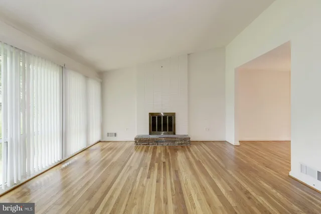 a view of a livingroom with wooden floor and a fireplace