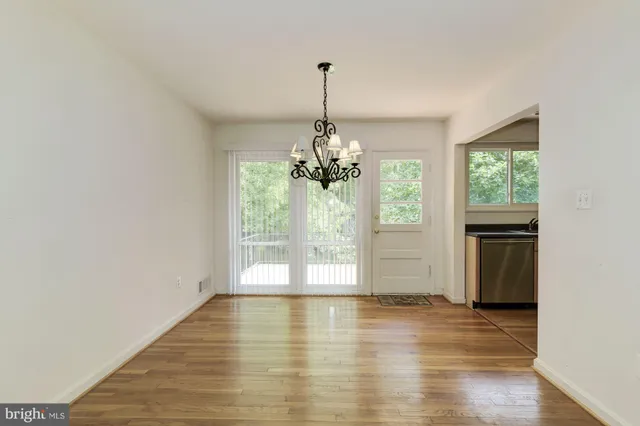 a view of a room with wooden floor chandelier and windows