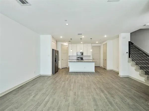 a view of a kitchen with refrigerator and wooden floor