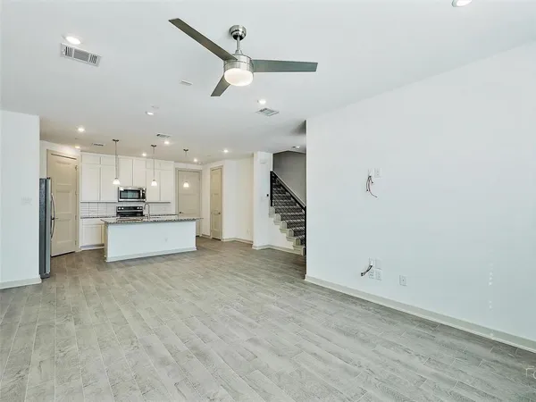 an open kitchen with a refrigerator and white cabinets