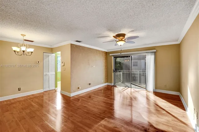 an empty room with wooden floor and a ceiling fan