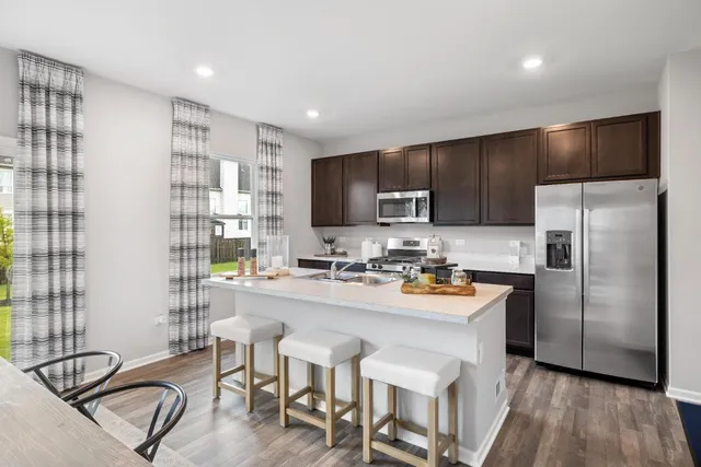 a kitchen with a refrigerator a stove a sink and chairs