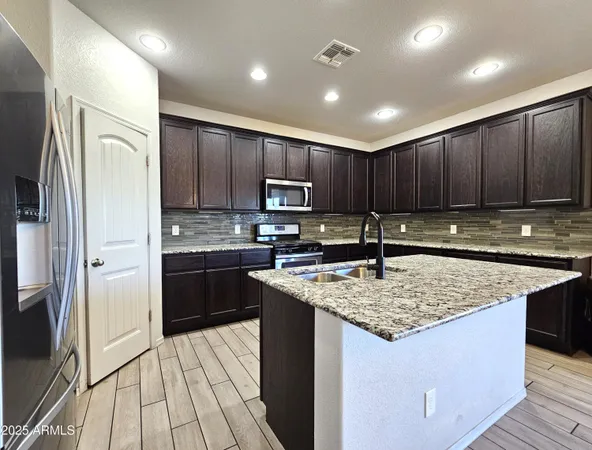 a kitchen with stainless steel appliances wooden cabinets a stove a microwave and a refrigerator