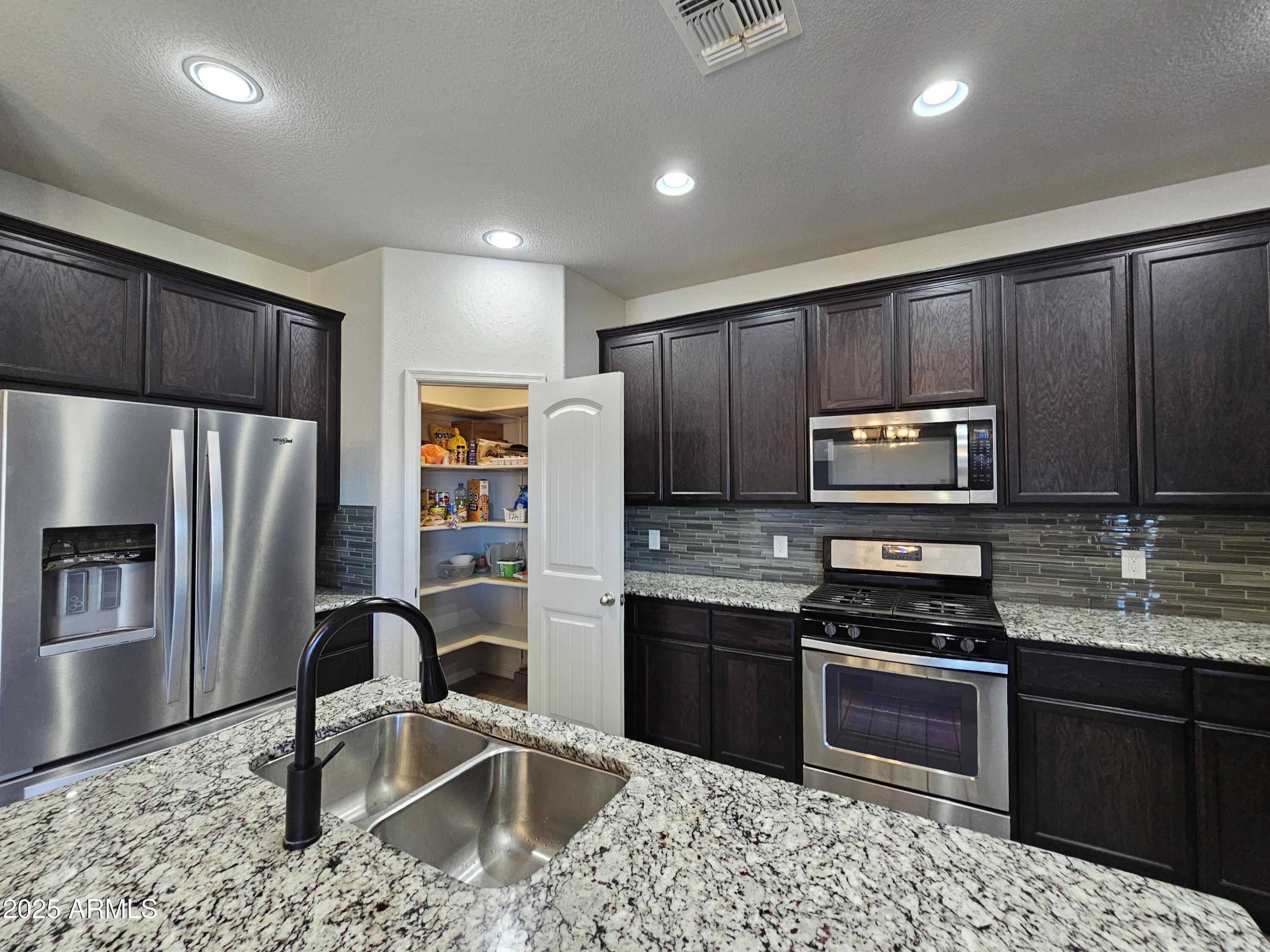 3443 Rhapsody Drive Sierra Vista, AZ 85650 - Photo 7 of 28 a kitchen with stainless steel appliances wooden cabinets a stove a microwave and a refrigerator