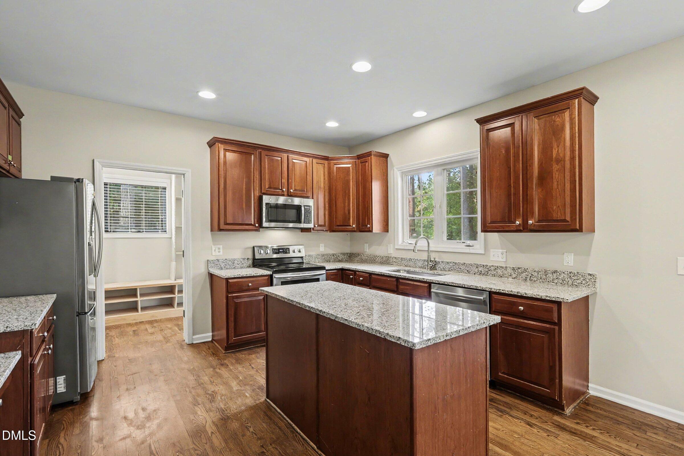 1001 Denfield Court Raleigh, NC 27615 - Photo 4 of 44 a kitchen with stainless steel appliances granite countertop wooden cabinets a stove top oven a sink and dishwasher