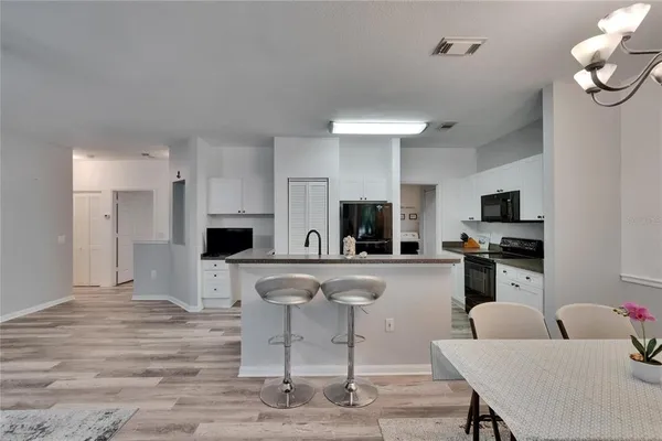 a dining room with wooden floor a chandelier a wooden table and chairs