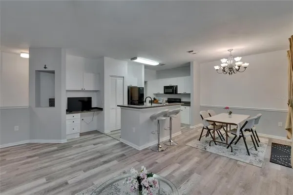 a kitchen with stainless steel appliances granite countertop a stove top oven a sink dishwasher a dining table and chairs with wooden floor