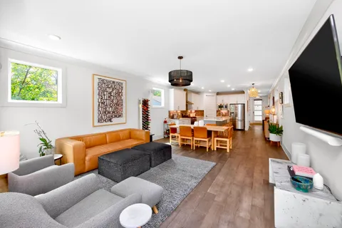 a living room with furniture kitchen view and a large window