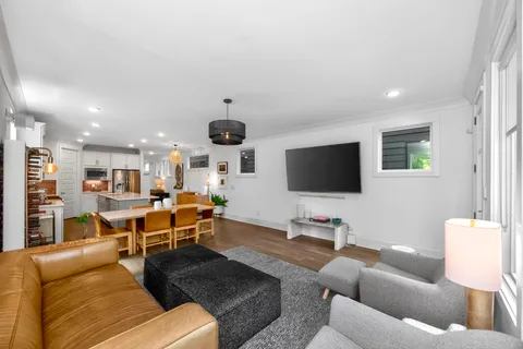 a living room with furniture kitchen view and a flat screen tv