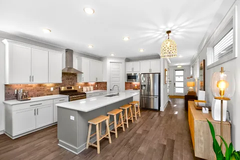 a kitchen with stainless steel appliances granite countertop a stove top oven a sink dishwasher and a refrigerator with wooden floor