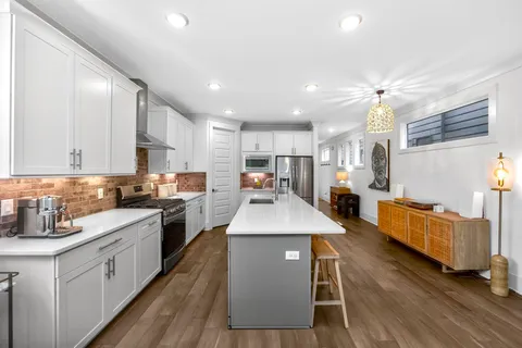 a kitchen with stainless steel appliances granite countertop a stove top oven a sink dishwasher and a refrigerator with wooden floor