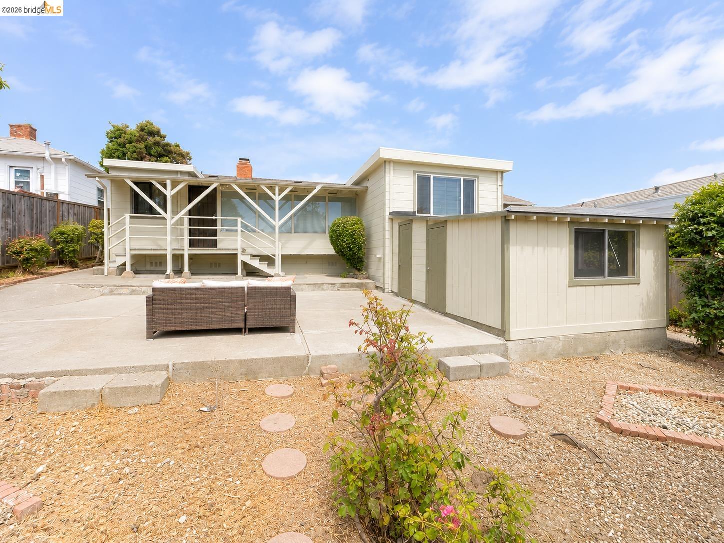 810 Pierce Street Albany, CA 94706 - Photo 23 of 25 Exterior rear of the property featuring a concrete patio, wood fencing, and an auxiliary structure with dual access doors and a window