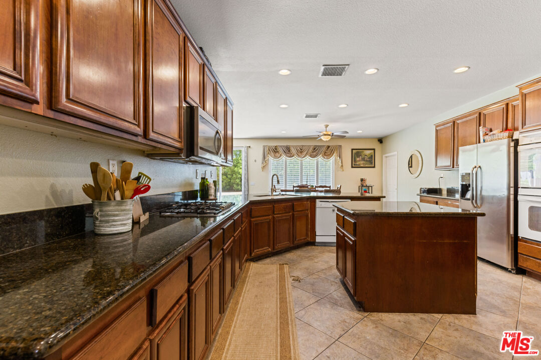 8256 Daisy Lane Riverside, CA 92508 - Photo 10 of 29 a kitchen with stainless steel appliances granite countertop counter space a sink a stove and a refrigerator