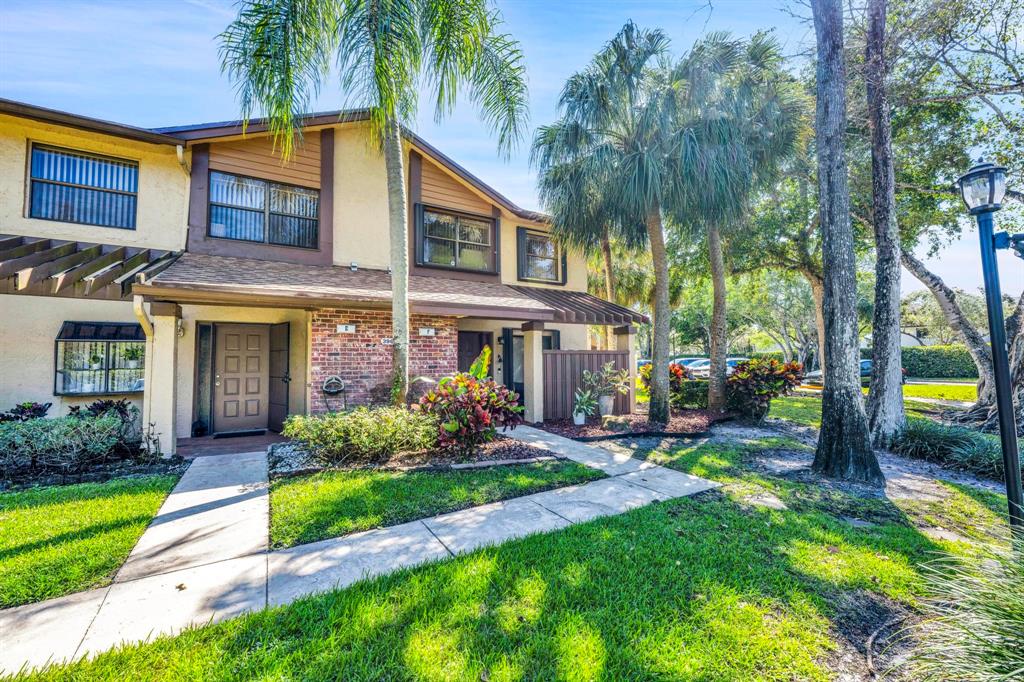 3963 Cocoplum Circle, Unit F Coconut Creek, FL 33063 - Photo 1 of 35 a front view of a house with garden and trees